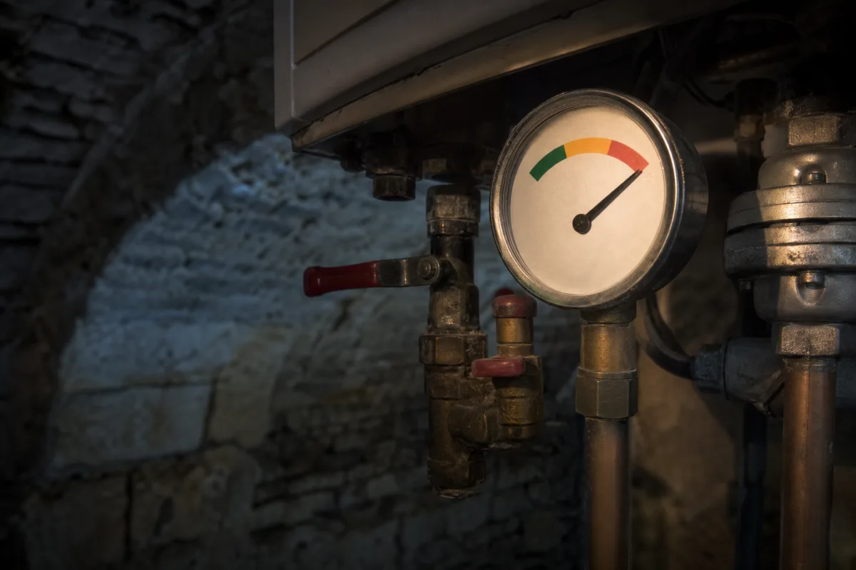 Manomètre de chaudière éclairé à la lampe frontale dans une chaufferie ancienne