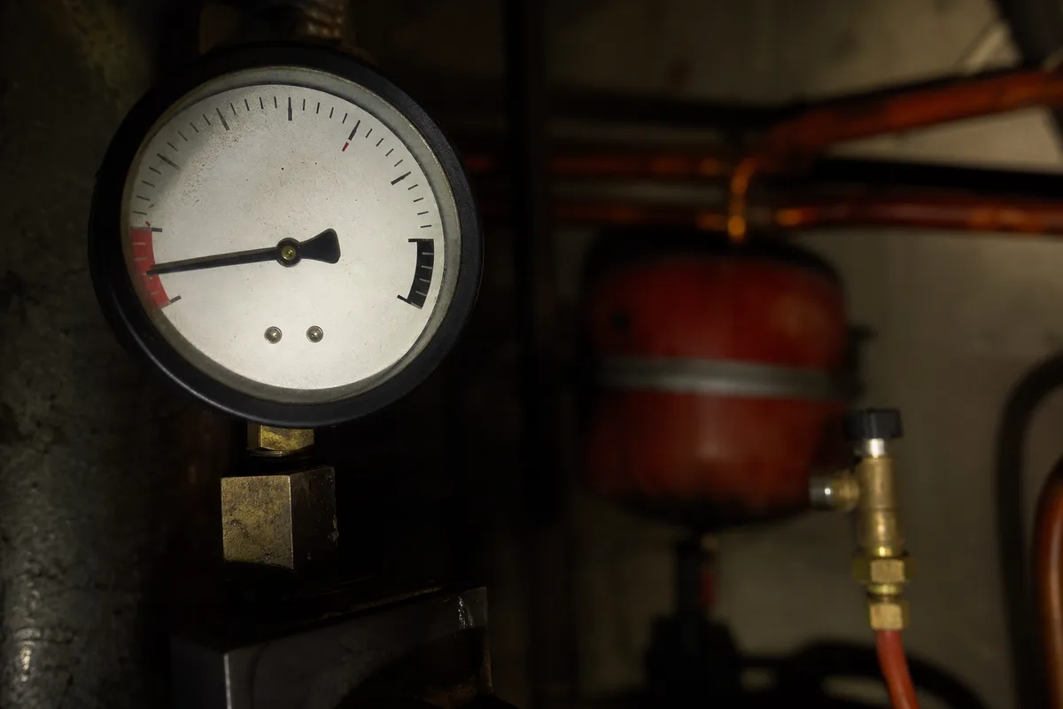 Manomètre de chaudière éclairé à la lampe frontale dans une buanderie de nuit
