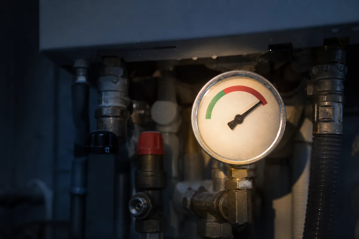 Manomètre de chaudière éclairé à la lampe frontale dans une chaufferie sombre